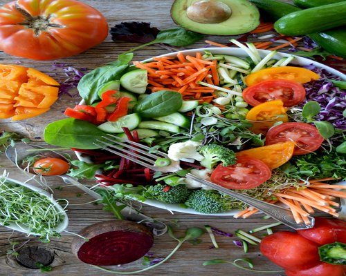 A clean assortment of fresh daily vegetables including sliced avocados, spinach leaves, and red tomatoes